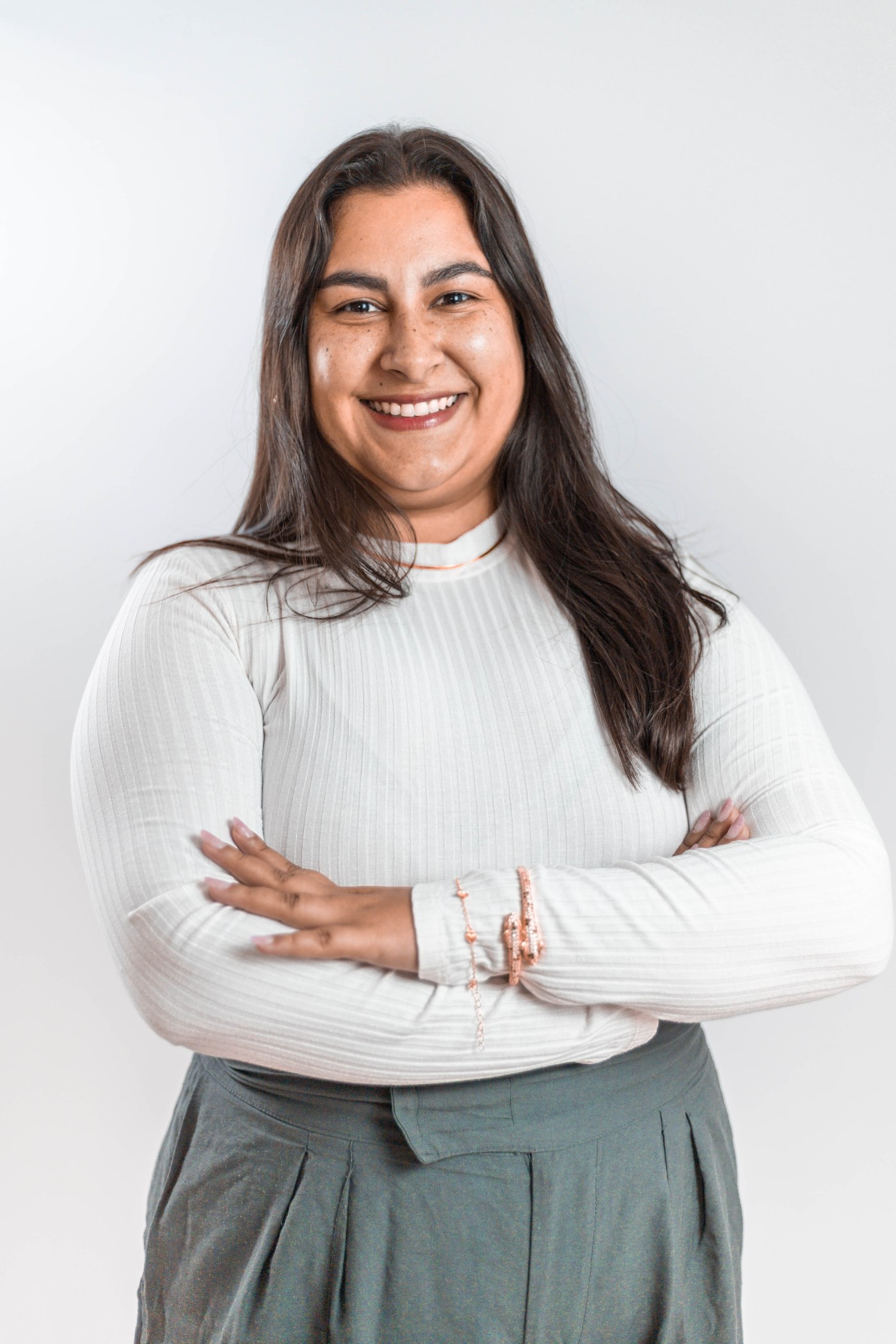 Aline Moitinho, psicóloga clínica, de braços cruzados, olhando para a câmera